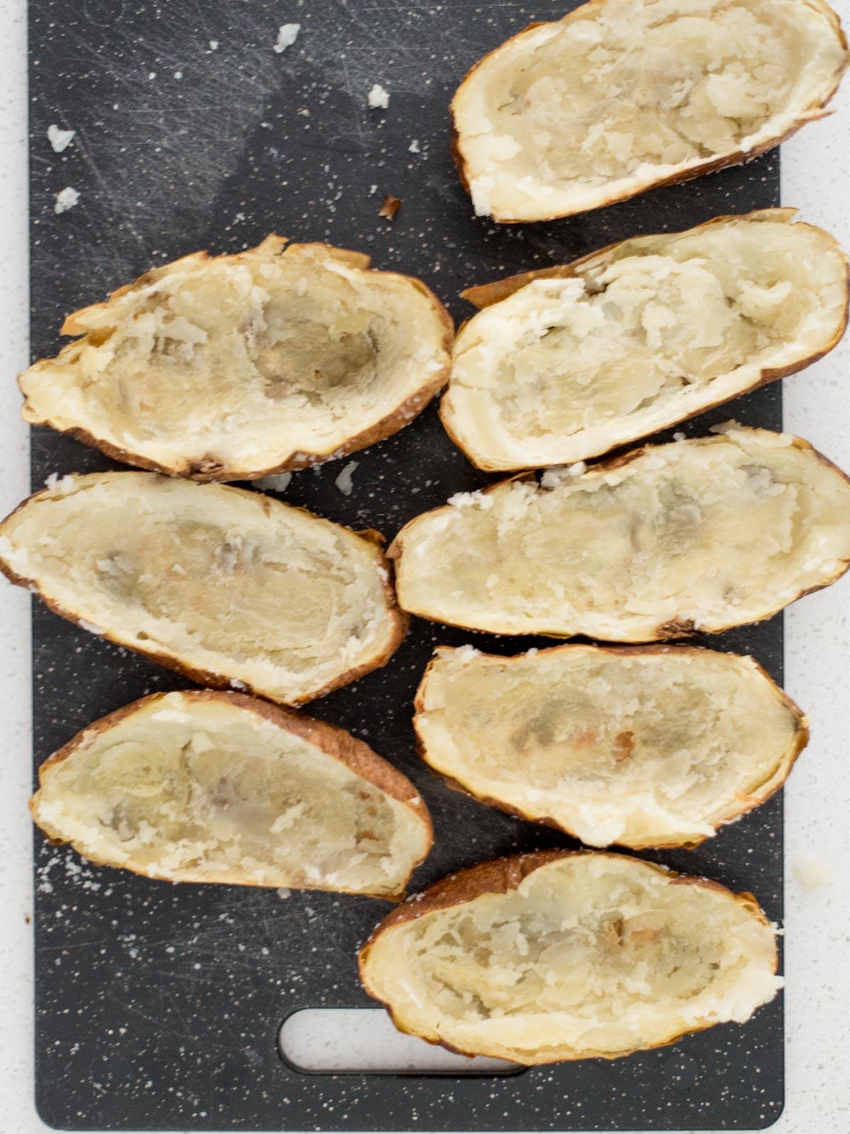 Patate Doppia Cottura in Friggitrice ad Aria 9 Buccia di patate su un tagliere con le patate rimosse dal centro.
