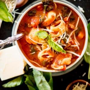 Tortellini al Pomodoro alla Fiorentina 9 Zuppa di spinaci e tortellini in una ciotola guarnita con parmigiano grattugiato e basilico fresco.