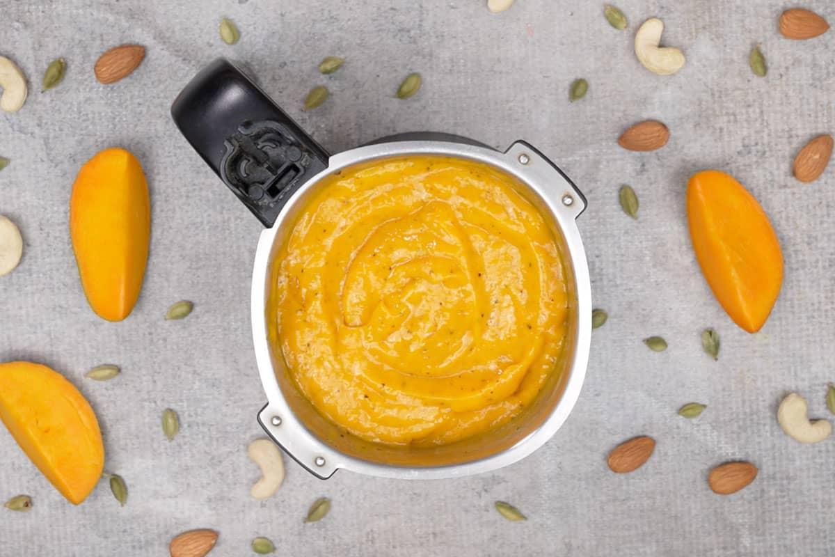 Aamras 9 Aamras pronto, guarnito con mandorle e pistacchi, servito freddo in una ciotola.