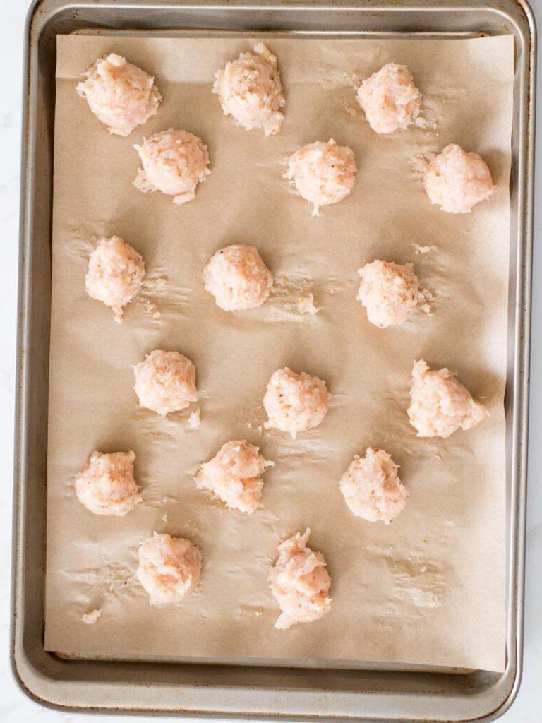 Polpette di pollo caramellate 10 Polpette di pollo su una teglia rivestita di carta forno