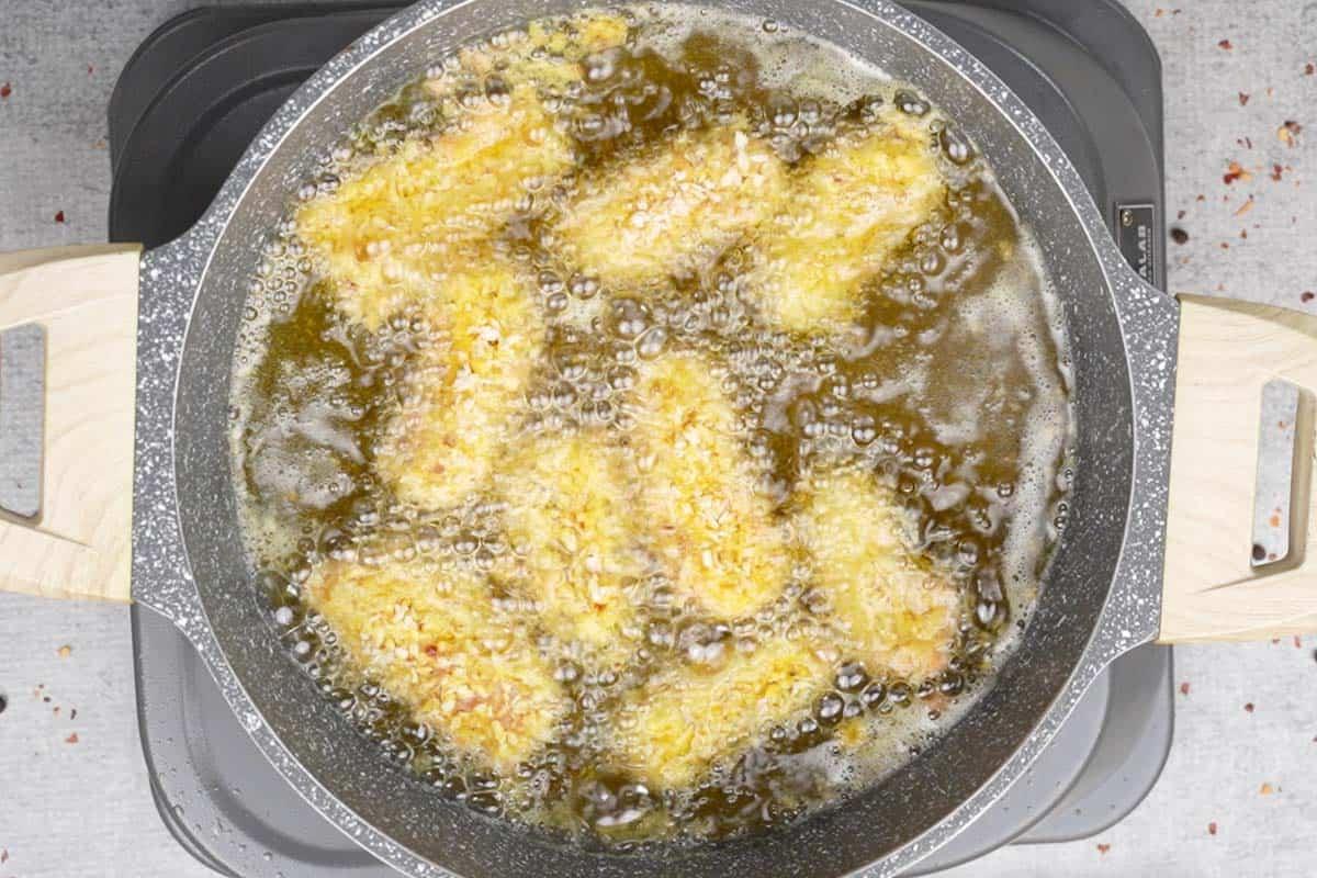 Bastoncini di pesce che friggono nell'olio caldo.