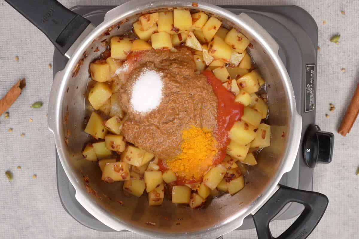 Passata di pomodoro, pasta vindaloo, curcuma in polvere e sale aggiunti alla pentola a pressione.