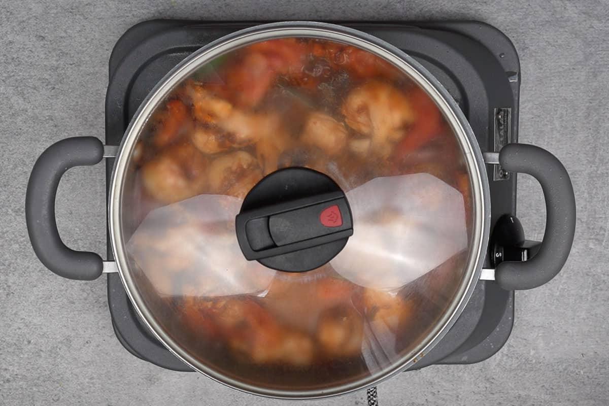 Pentola coperta con un coperchio, il curry sta cuocendo a fuoco lento.