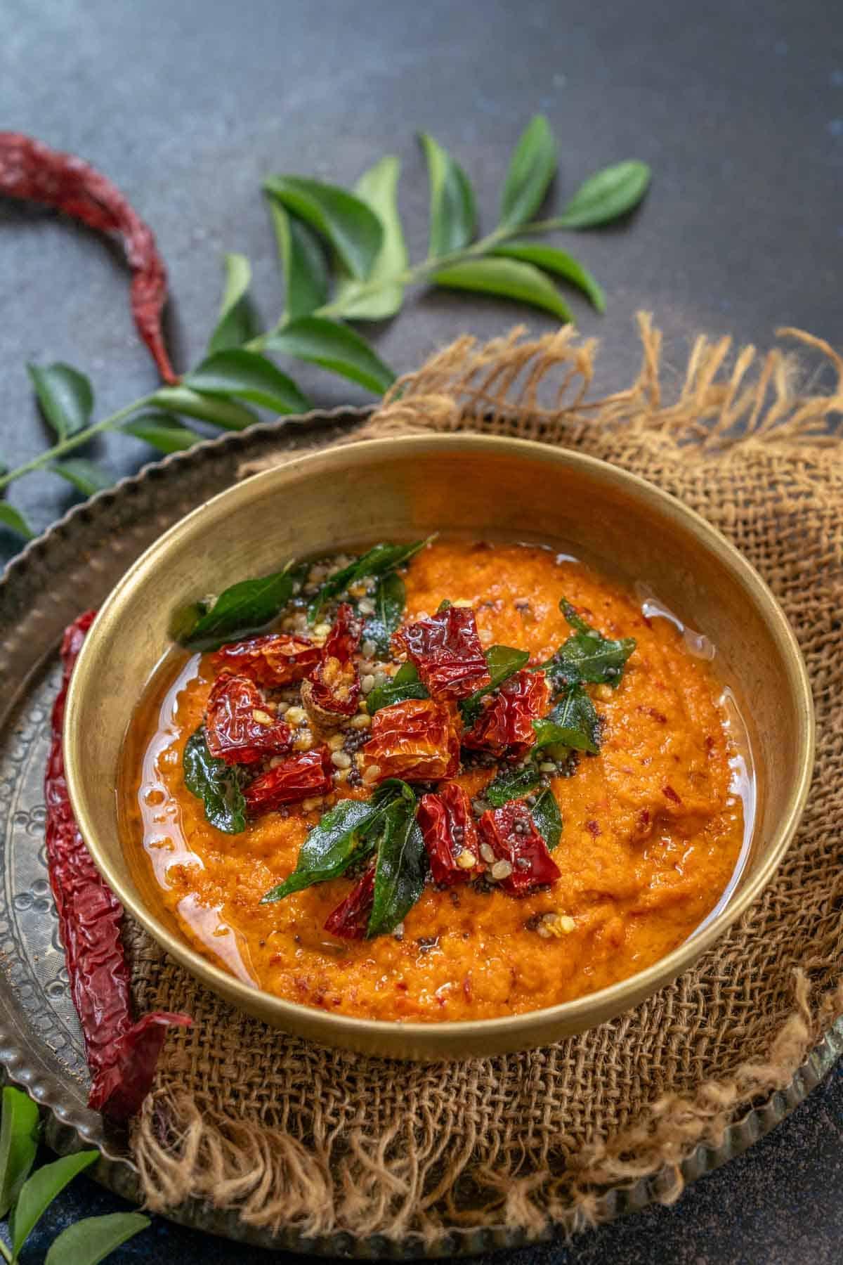 Chutney di Pomodoro e Cocco 2 Una ciotola di chutney di pomodoro e cocco, pronto per essere servito, con una consistenza liscia e un colore rosso-arancio invitante, guarnito con un tocco di tempering.