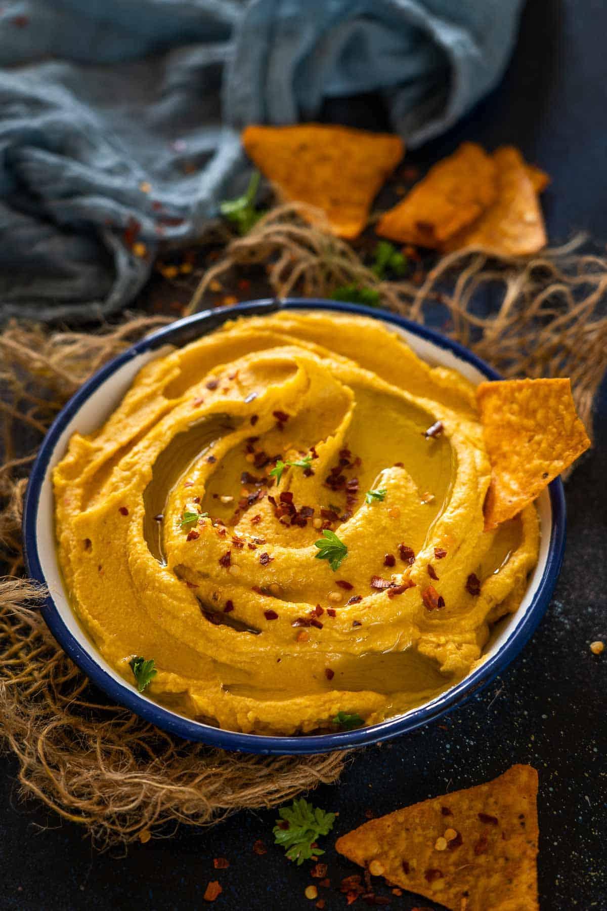 Hummus di Patata Dolce Arrosto 2 Hummus di patate dolci arrosto piccante servito in una ciotola.