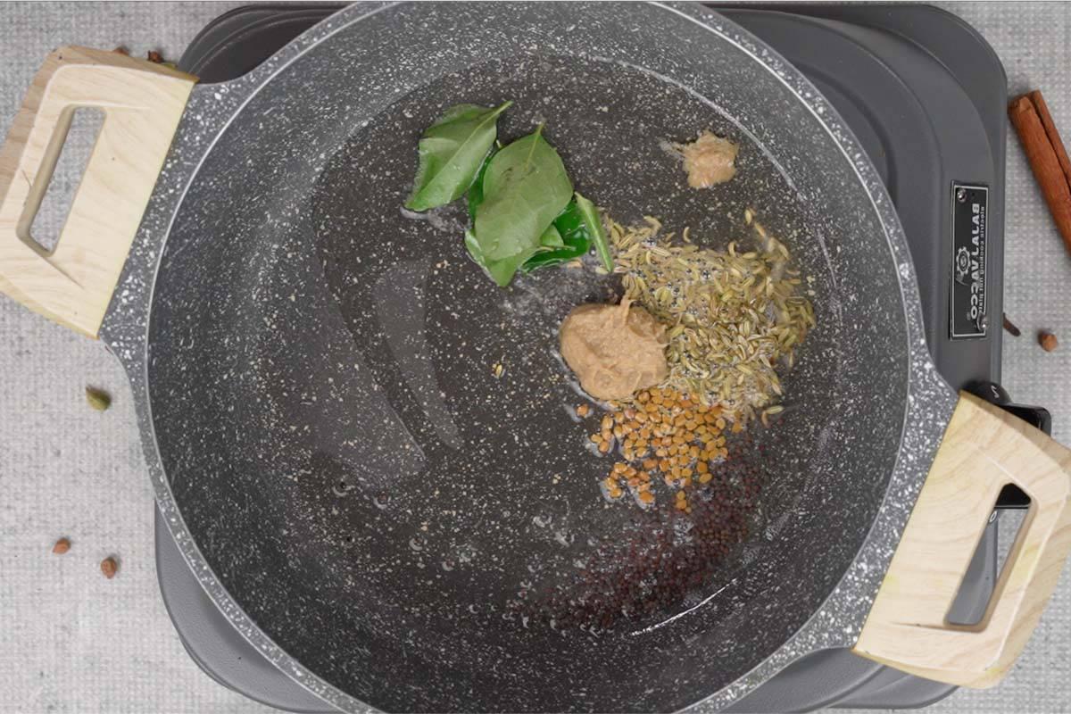Curry di ceci 10 Semi di senape, semi di finocchio, semi di fieno greco, pasta di zenzero e aglio e foglie di curry aggiunti all'olio di cocco caldo in una padella.