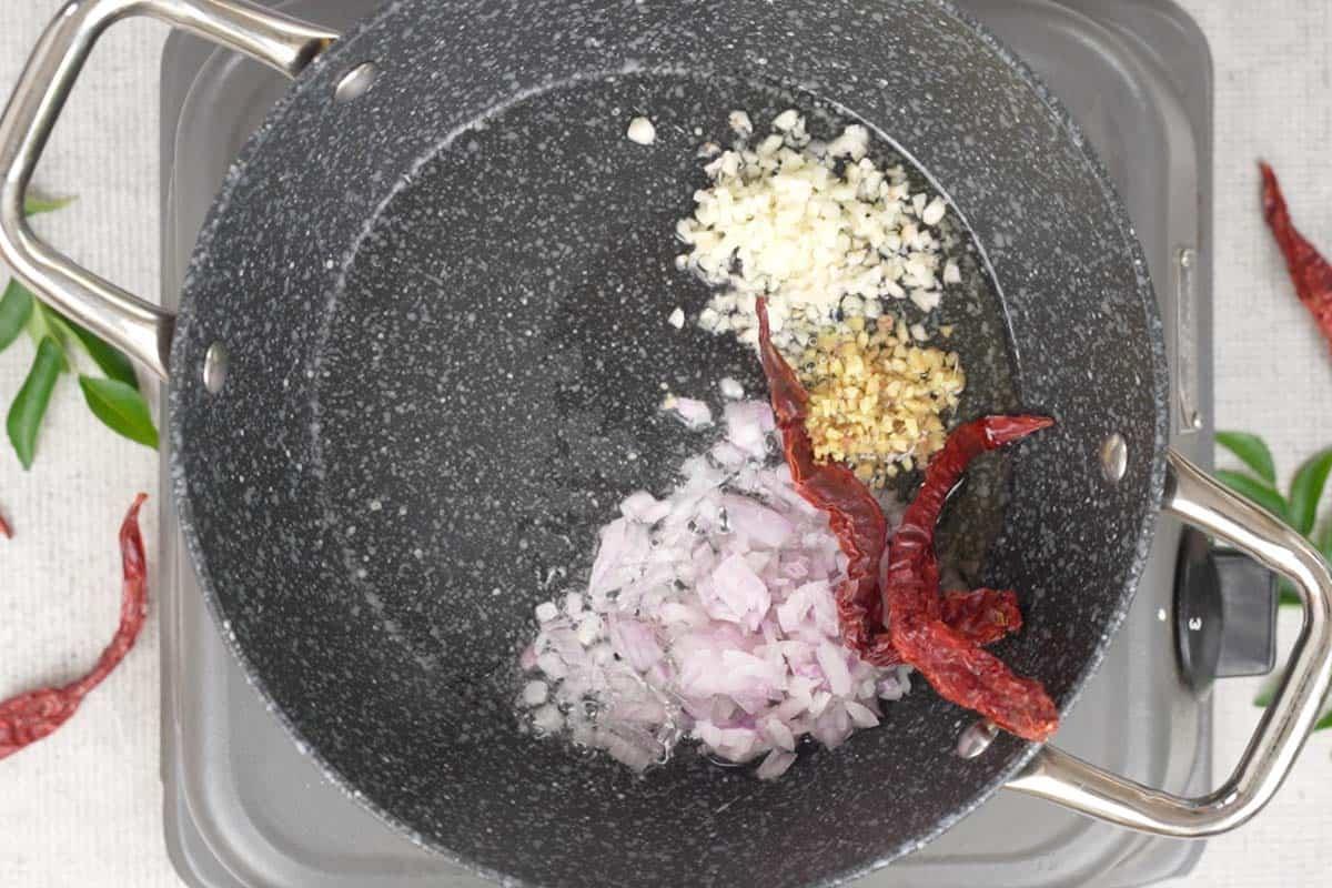 Chutney di Pomodoro e Cocco 3 Cipolle tritate, peperoncini rossi secchi, zenzero e aglio aggiunti a olio caldo in una padella, mentre vengono soffritti per il chutney, con un profumo che inizia a diffondersi.