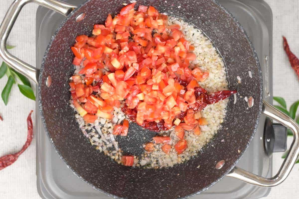 Chutney di Pomodoro e Cocco 4 Pomodori freschi tritati aggiunti alla padella con gli altri ingredienti aromatici, pronti per essere cotti e ammorbiditi, creando la base per il chutney.