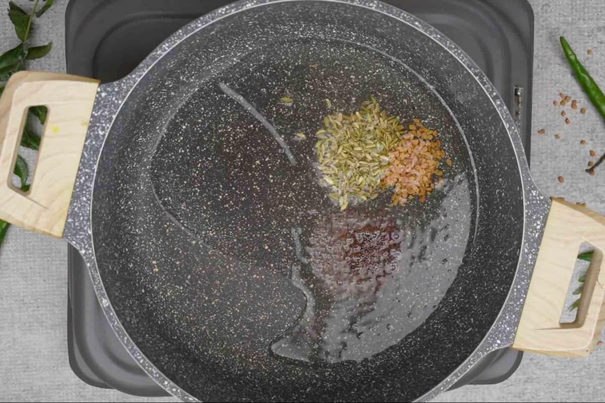 Semi di senape, semi di fieno greco e semi di finocchio aggiunti all'olio caldo.