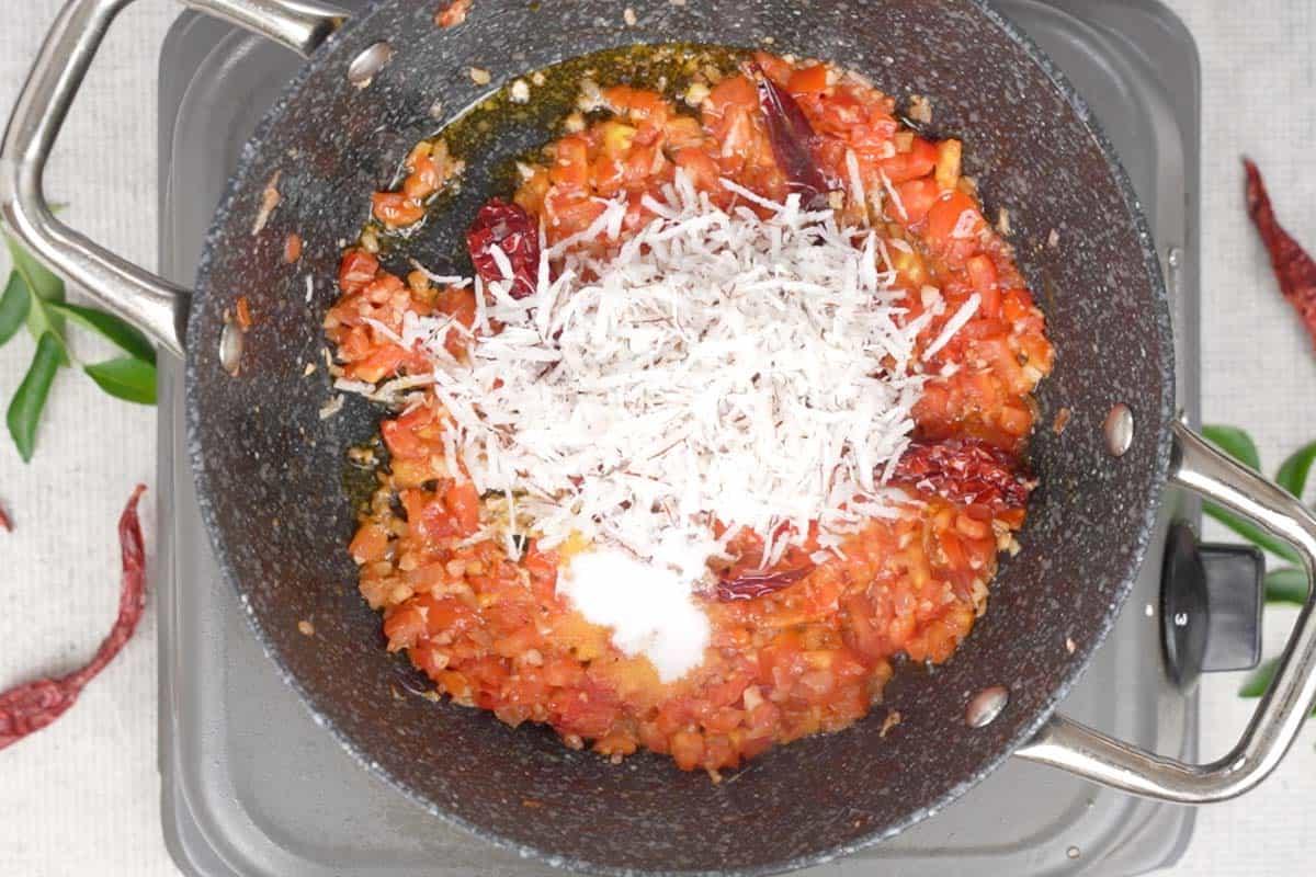 Chutney di Pomodoro e Cocco 5 Cocco fresco grattugiato e sale aggiunti alla padella, mescolati con la miscela di pomodoro e cipolla, pronti per una breve cottura.