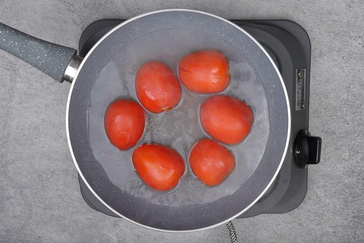 Kadhai di Carne Peshawari 5 Pomodori aggiunti nella pentola con acqua bollente.