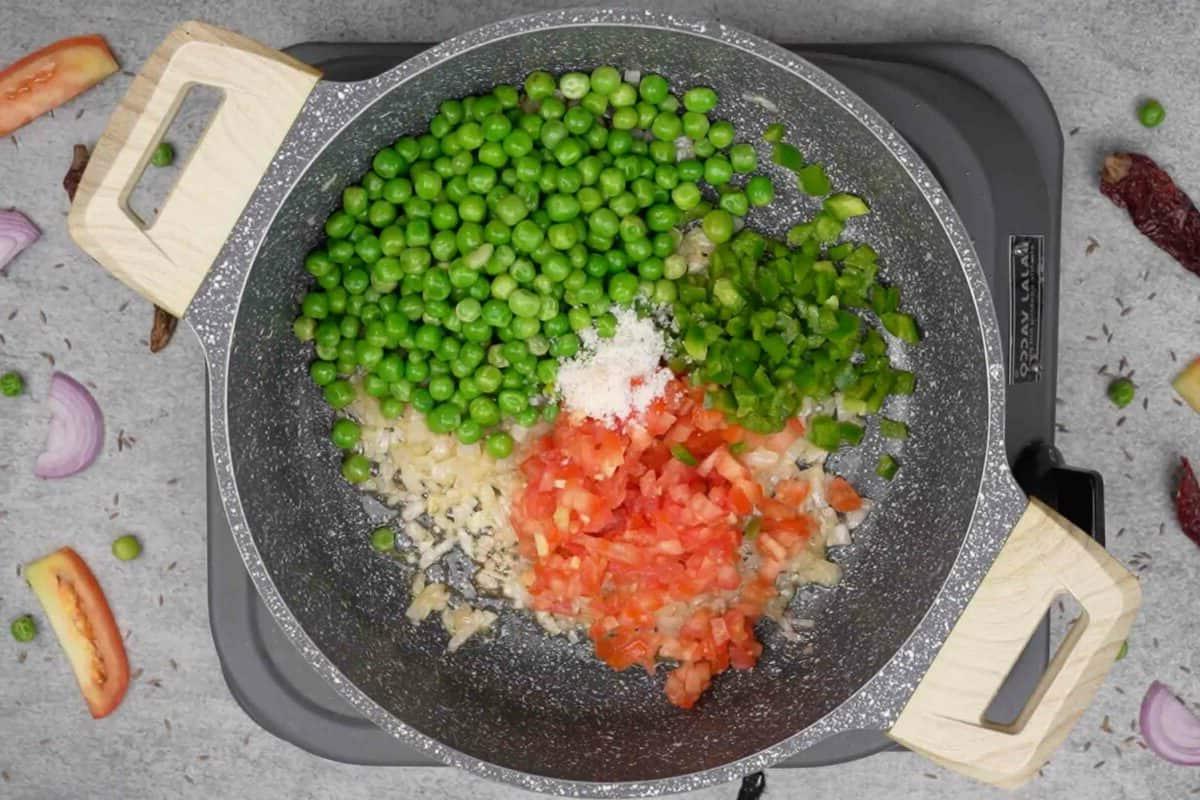 Maggi Tadka Formaggiosa 5 Verdure colorate e sale aggiunti alla padella, mescolati per cuocere.
