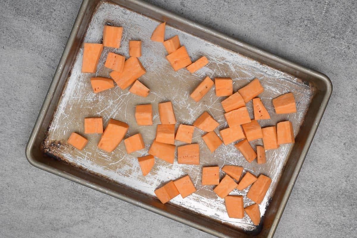 Hummus di Patata Dolce Arrosto 5 Cubetti di patate dolci disposti su una teglia da forno.