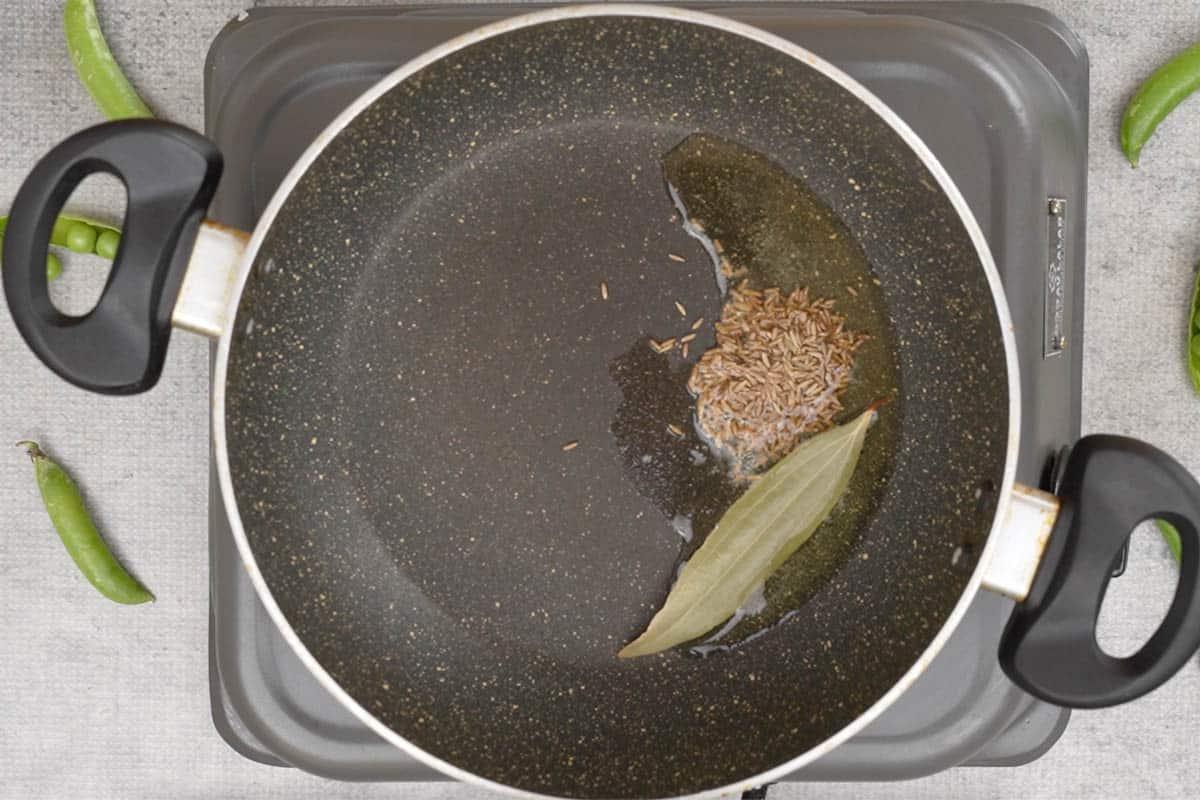 Fiocchi di riso e piselli 5 Semi di cumino e foglia di alloro aggiunti in padella.