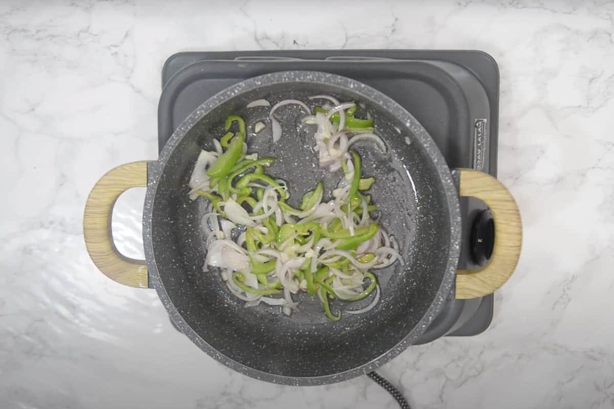 Paneer Jalfrezi 6 Cipolla e peperone cotti e messi da parte su un piatto, pronti per essere aggiunti successivamente.