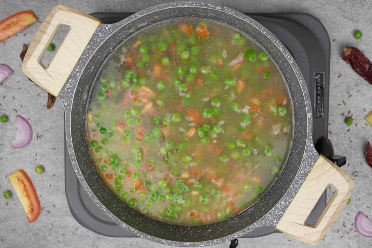 Maggi Tadka Formaggiosa 6 Acqua aggiunta alla padella con le verdure, pronta per essere portata a ebollizione.