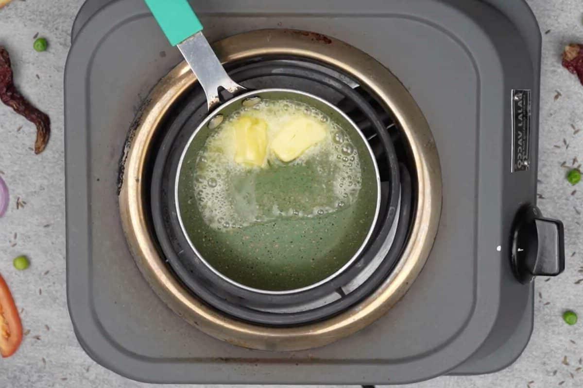 Maggi Tadka Formaggiosa 9 Burro e olio che si scaldano in una piccola padella per il tadka.