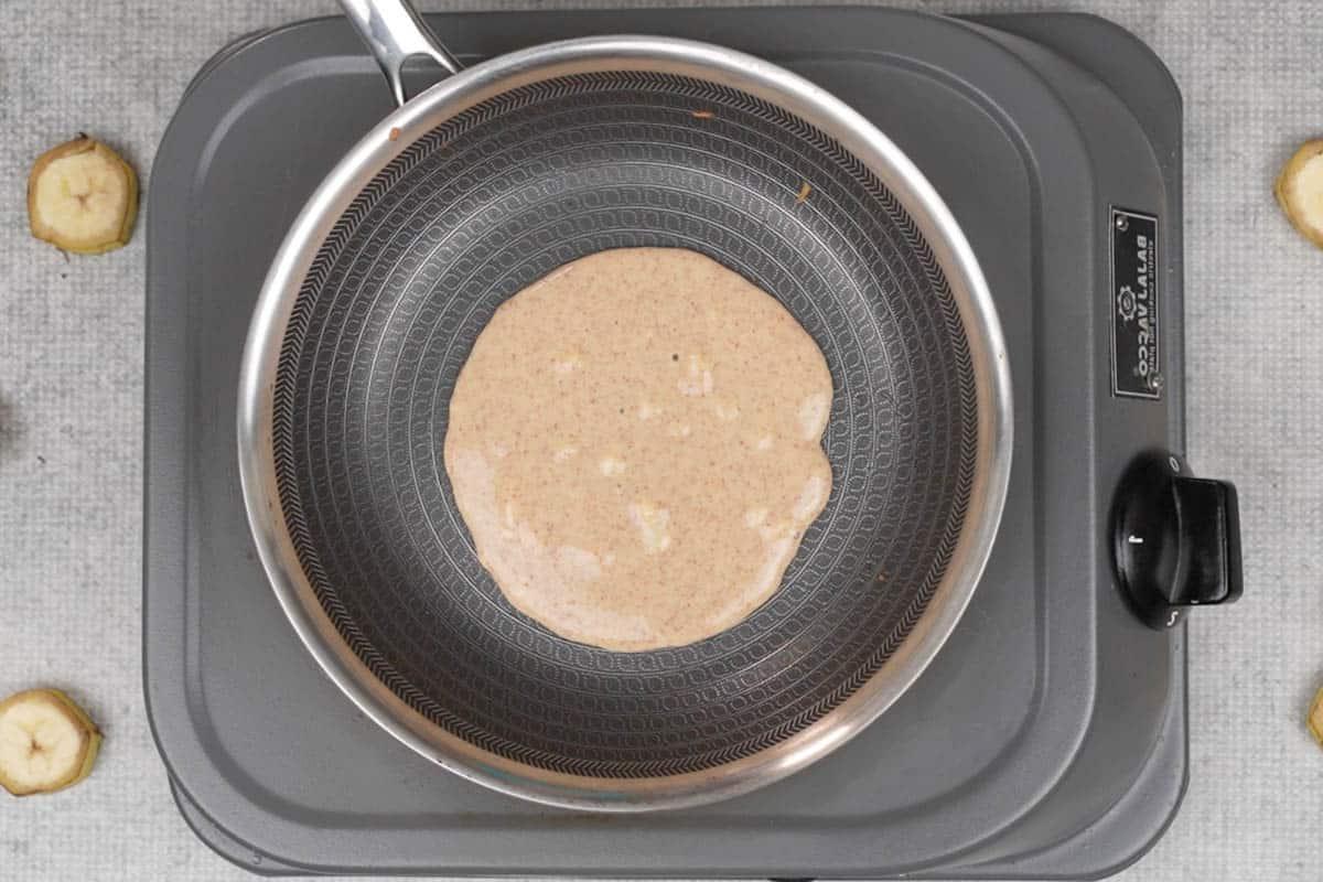 Pancakes di Ragi e Banana 10 Un mestolo di impasto versato al centro della padella.