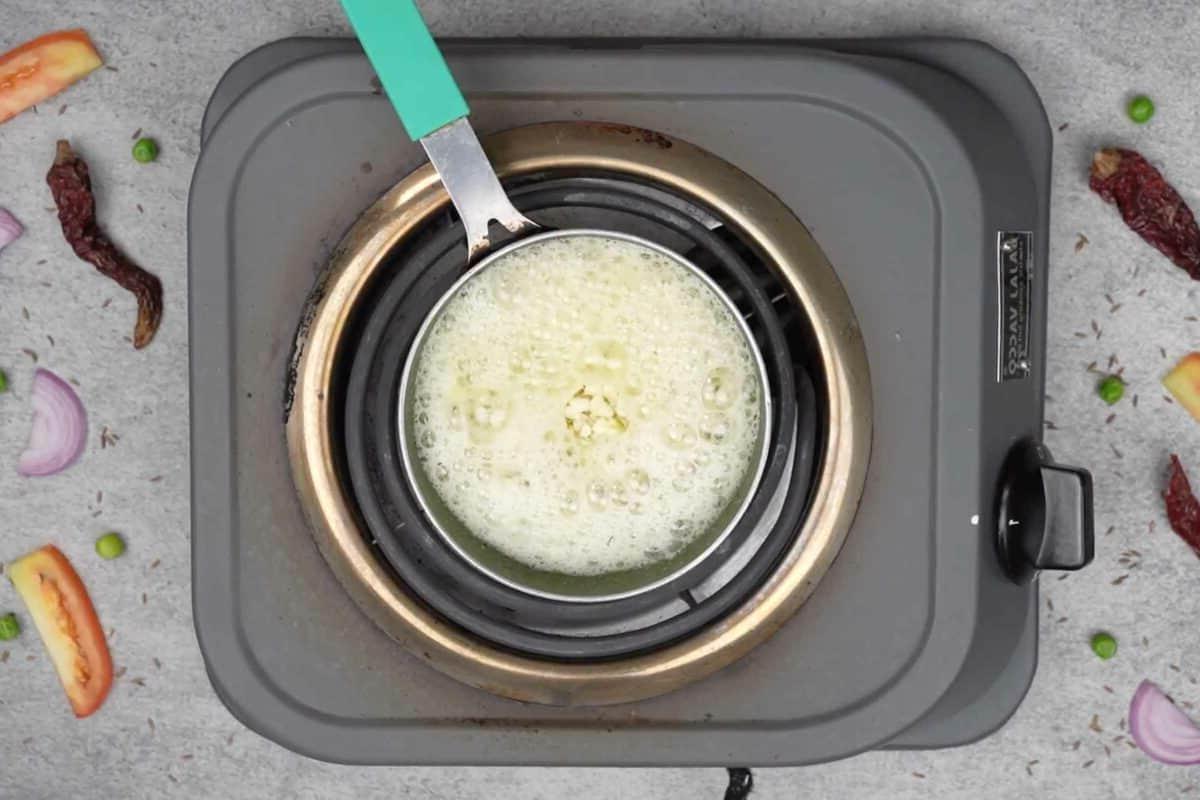 Maggi Tadka Formaggiosa 10 Semi di cumino e aglio tritato aggiunti alla padella, sfrigolanti nell'olio caldo.