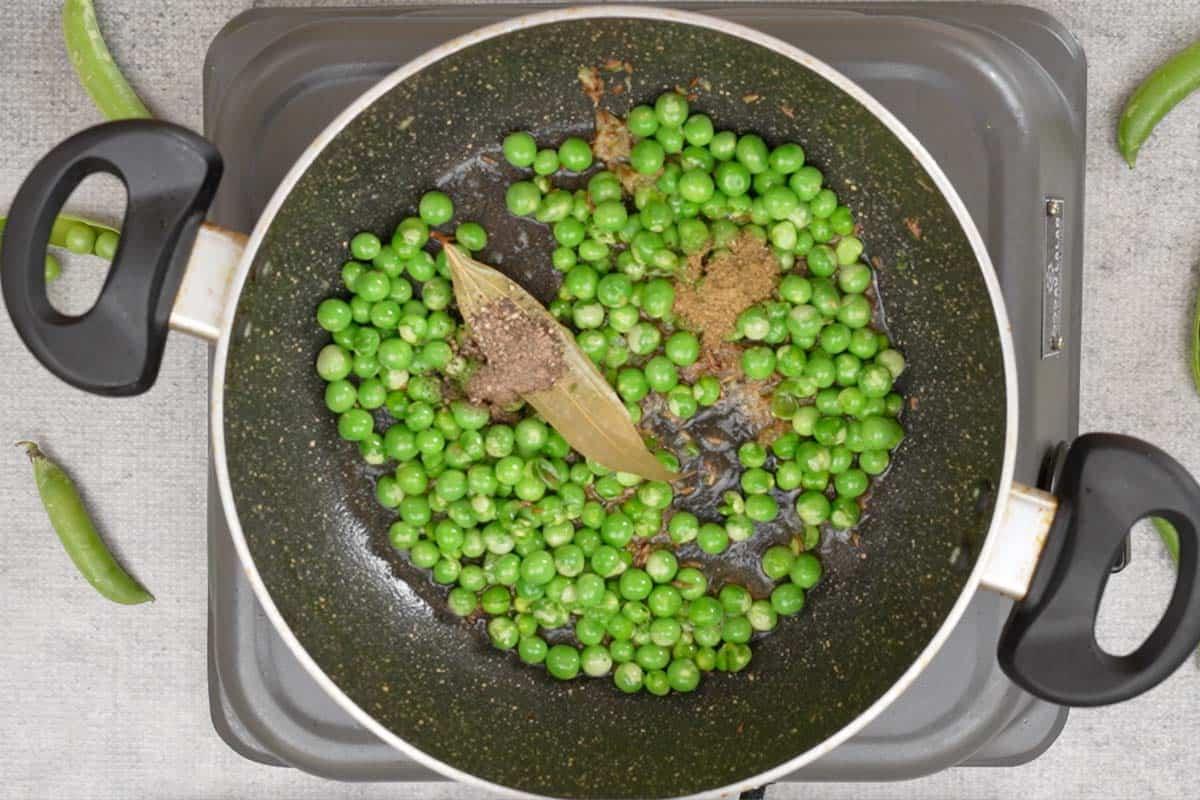 Fiocchi di riso e piselli 10 Garam masala e pepe nero in polvere aggiunti in padella.
