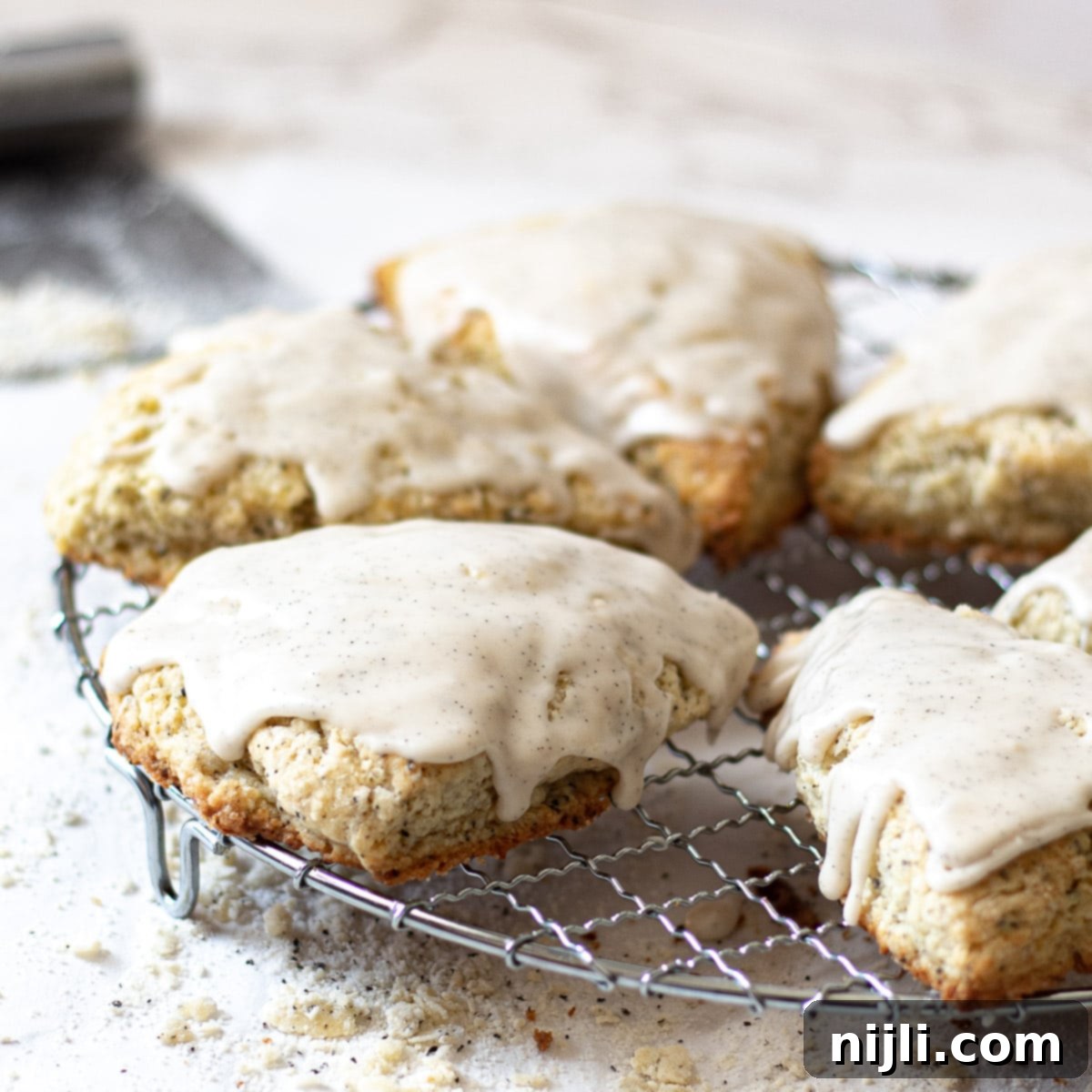 Aromatic Earl Grey Scones with Vanilla Bean Glaze 9 Earl Grey Scones on a wire rack drizzled with vanilla bean glaze
