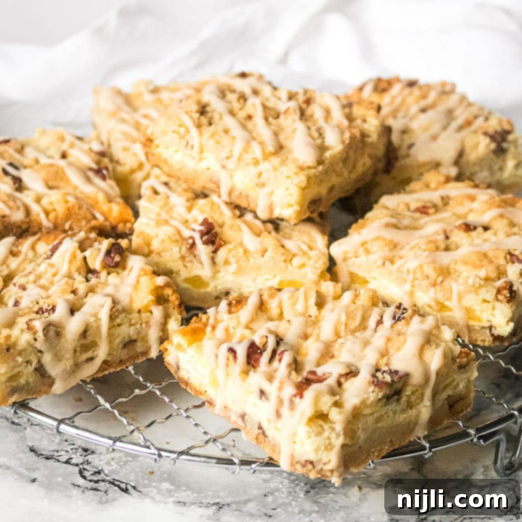 Pineapple bars displayed neatly on a wire cooling rack, showing the golden crumb topping and creamy filling.