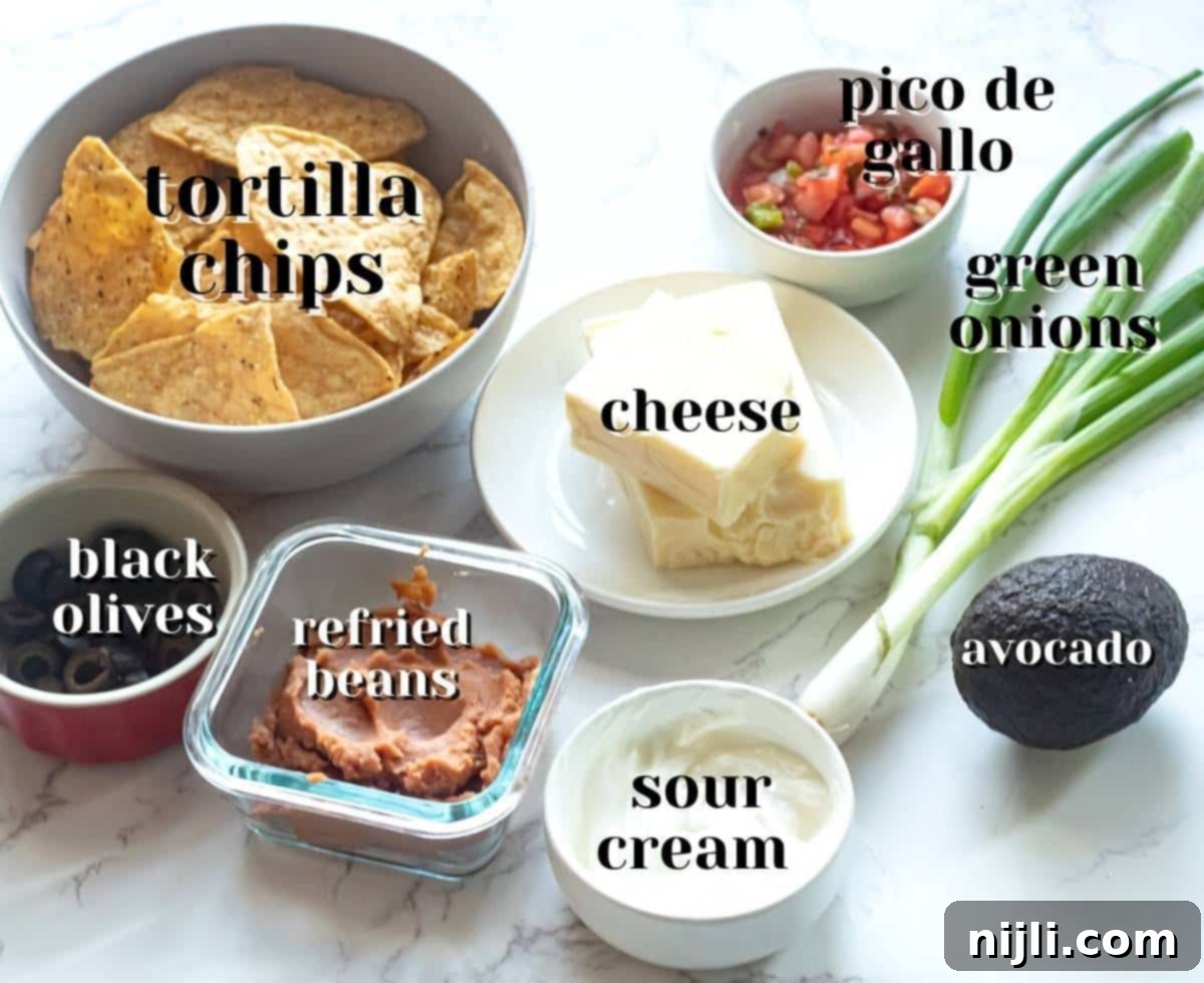 Crispy Air Fryer Nachos 4 Various essential ingredients for delicious air fryer nachos displayed in separate bowls, including tortilla chips, shredded cheese, refried beans, and fresh pico de gallo.