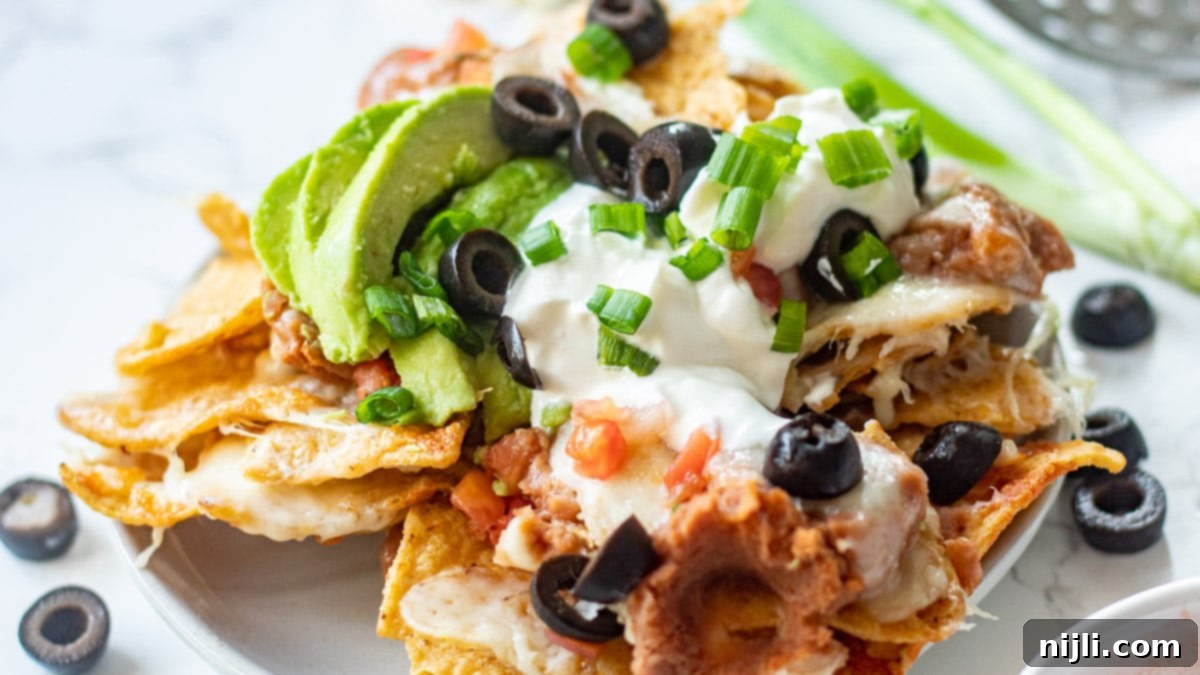 Crispy Air Fryer Nachos 5 Close-up view of perfectly cooked and melted cheese nachos in an air fryer basket, showing crispy chips and bubbly cheese, ready for fresh toppings.