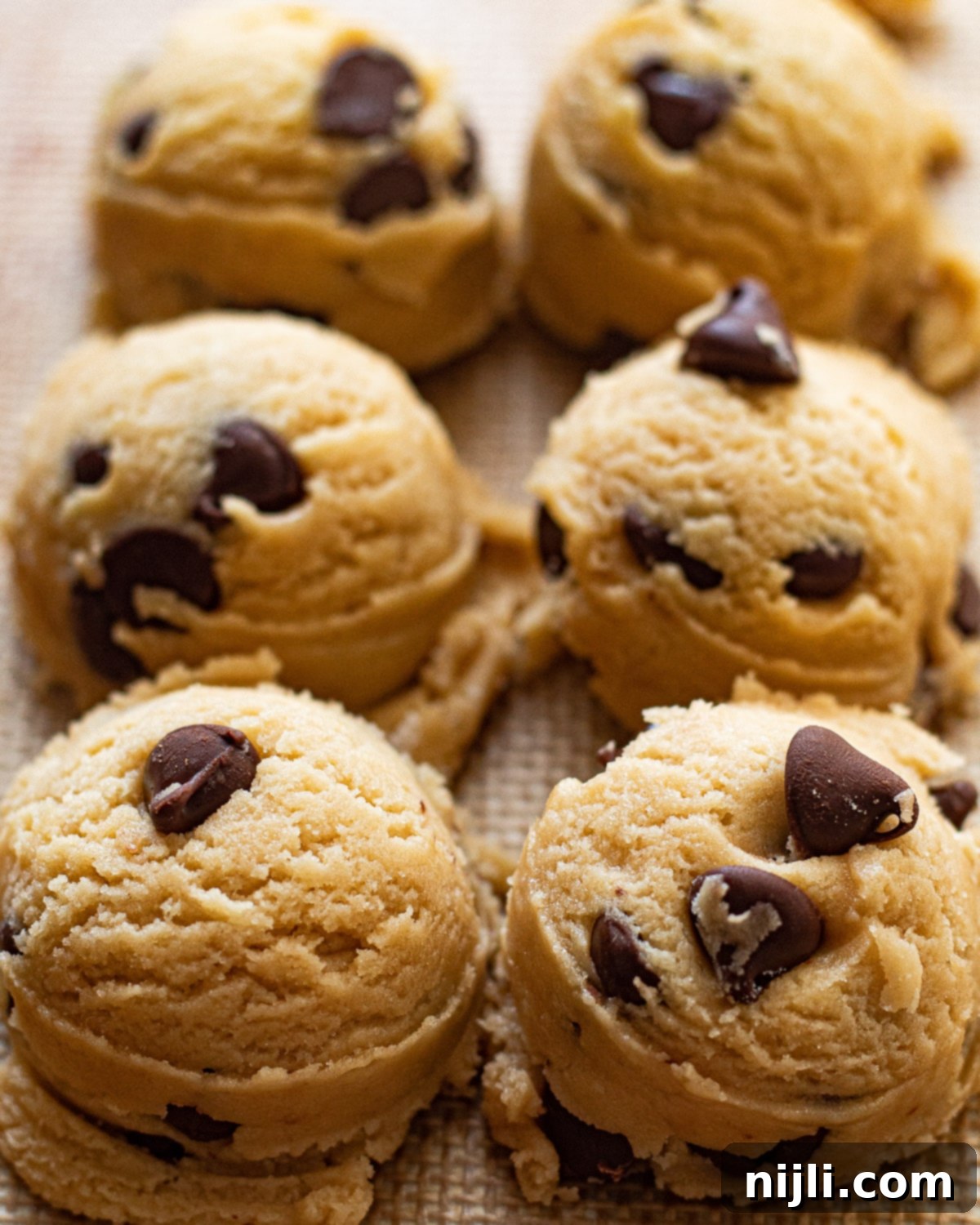 Vegan Chocolate Chip Cookies 5 Scoops of uncooked dairy free cookie dough on a baking sheet, ready for the oven