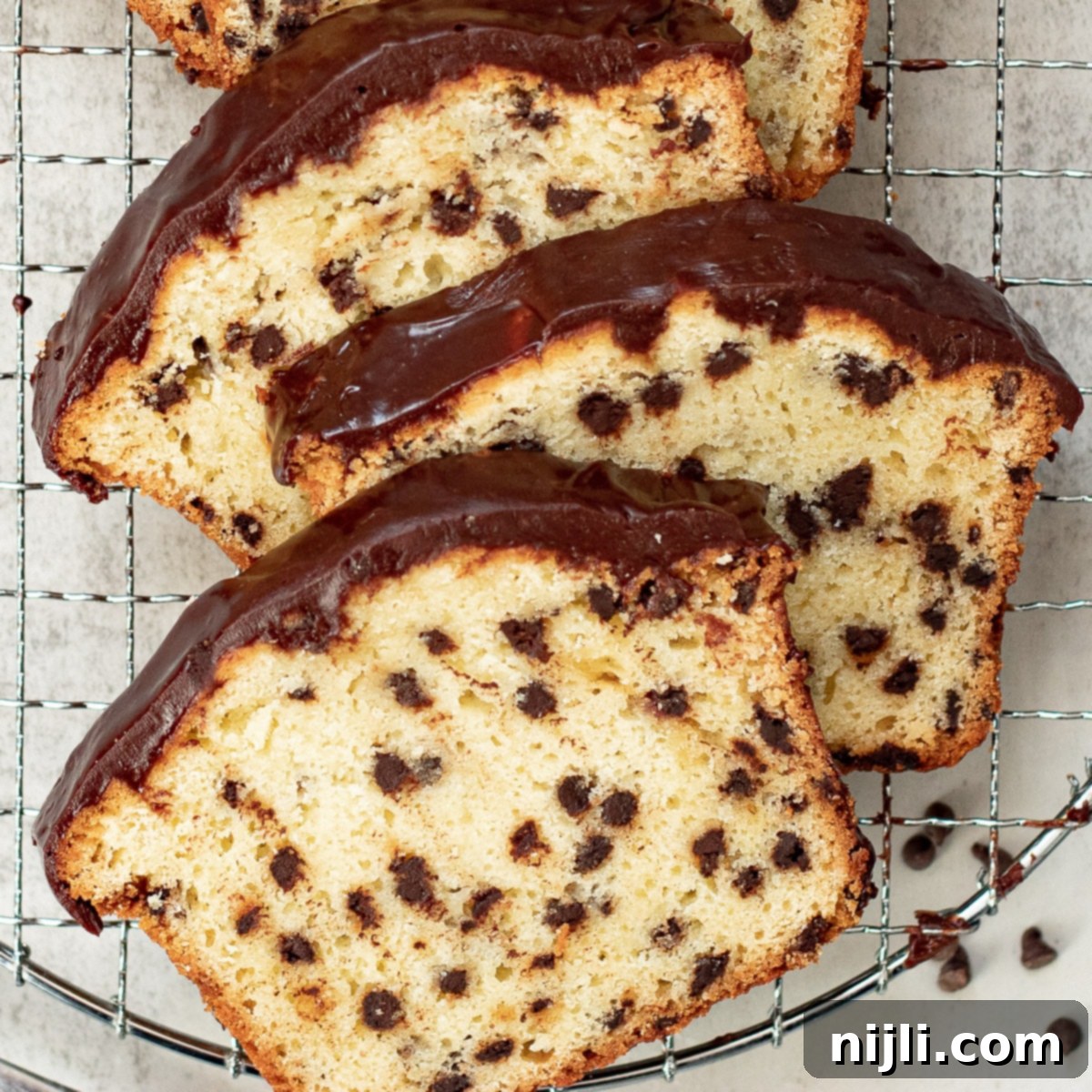 Decadent Chocolate Chip Loaf 2 Slices of moist sour cream chocolate chip loaf cake with chocolate glaze on a serving tray, ready to be enjoyed.