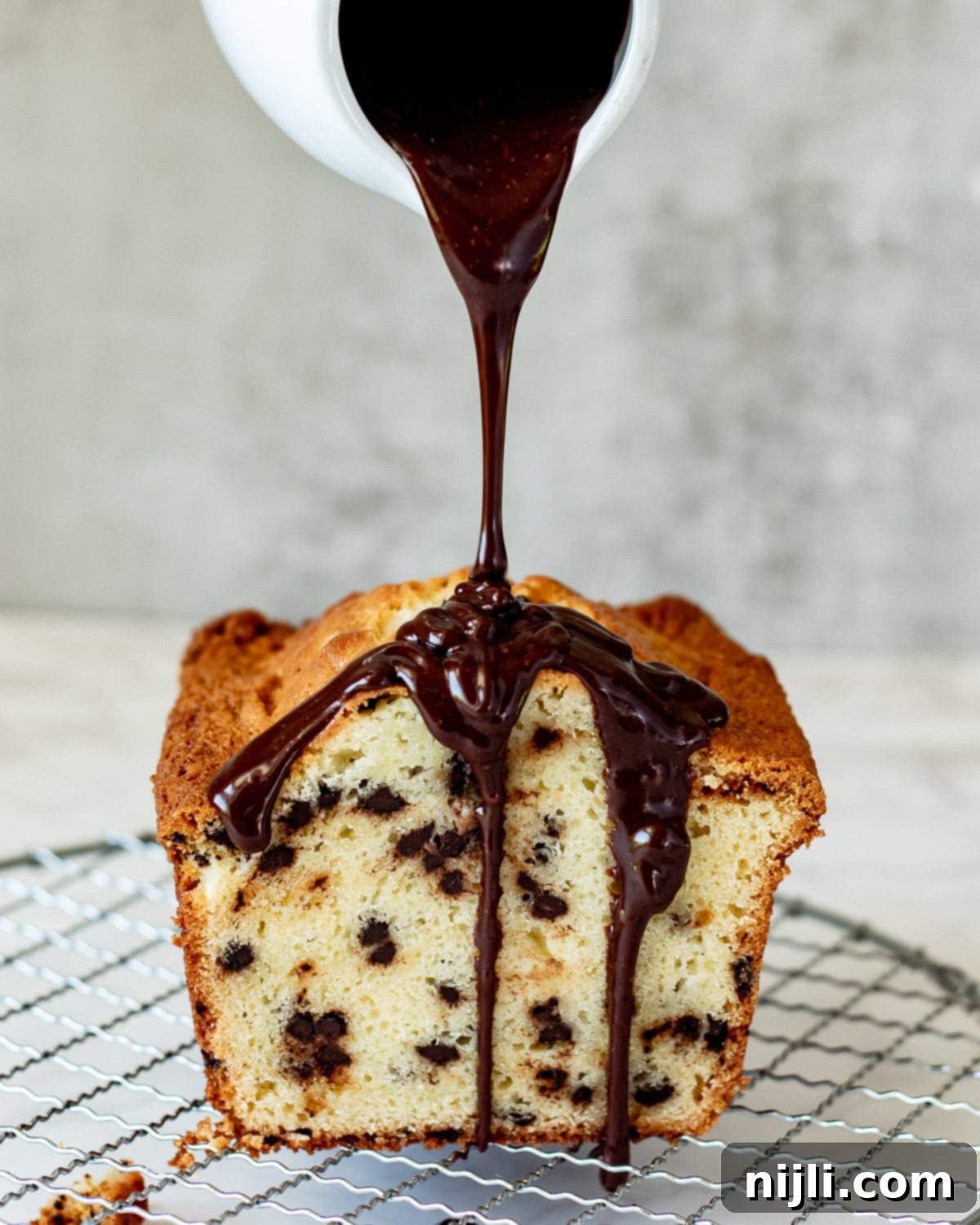 Decadent Chocolate Chip Loaf 5 A freshly baked sour cream chocolate chip loaf cake generously topped with a shiny chocolate ganache glaze, presented beautifully.