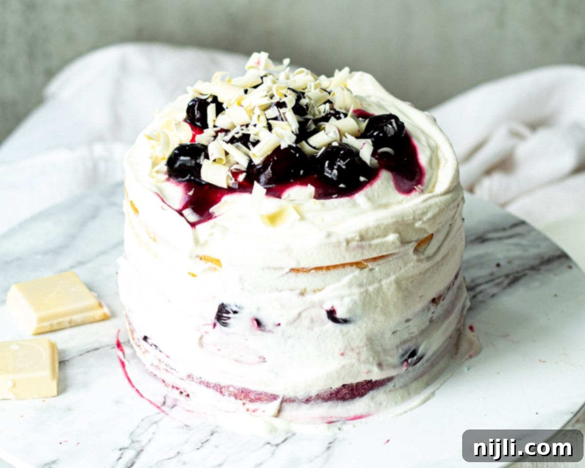 Snow-Kissed Forest Cake 5 A pristine White Forest Cake, garnished with fresh cherries and white chocolate shavings, emphasizing its delicious taste and celebratory appeal.