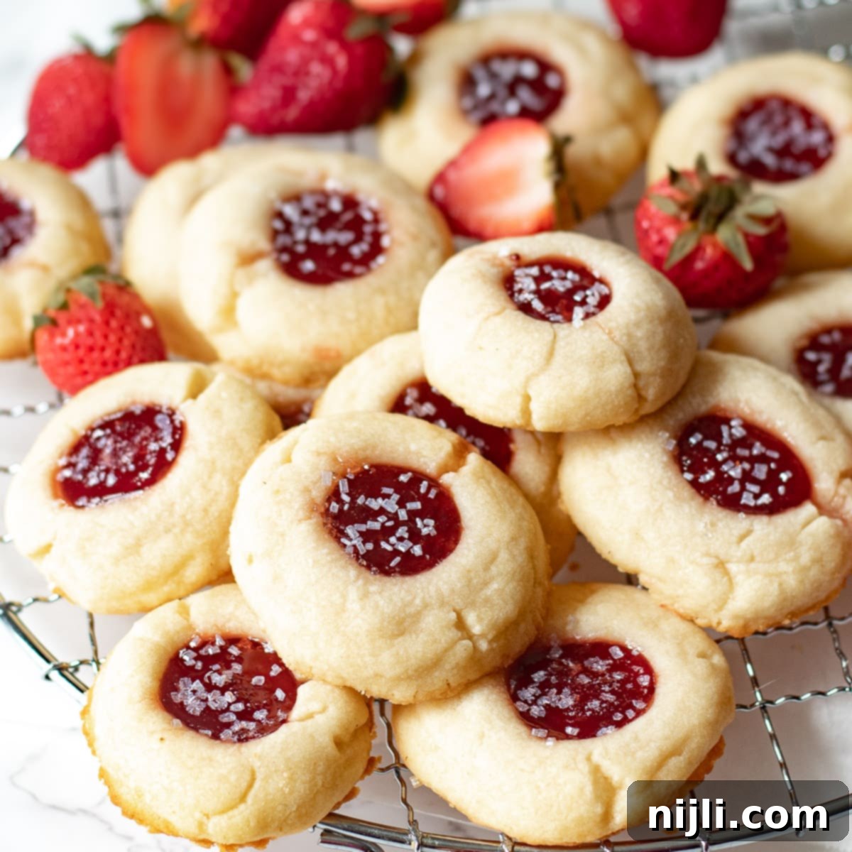 Strawberry Shortbread Delights 2 strawberry jam shortbread cookies on a wire rack