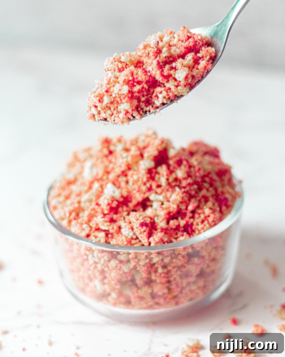 Classic Strawberry Shortcake Crumble 3 A spoonful of vibrant strawberry crunch topping, showcasing the delightful blend of red freeze-dried strawberries and golden cookie crumbles.