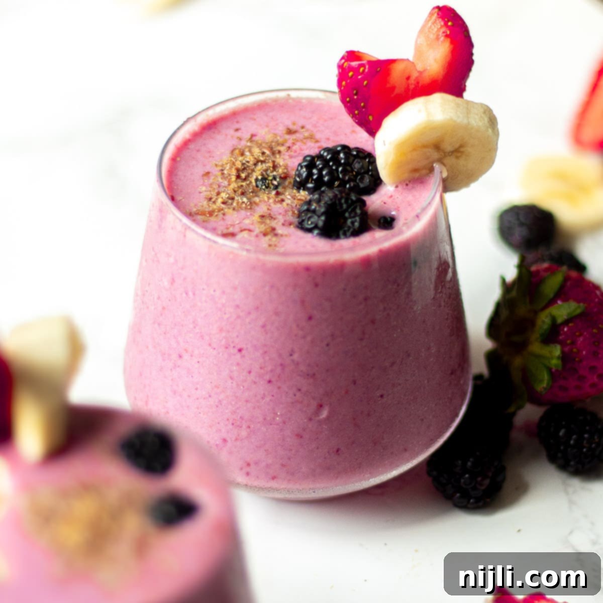 Triple Berry Banana Delight 2 blackberry strawberry banana smoothie in a class with fruit garnish