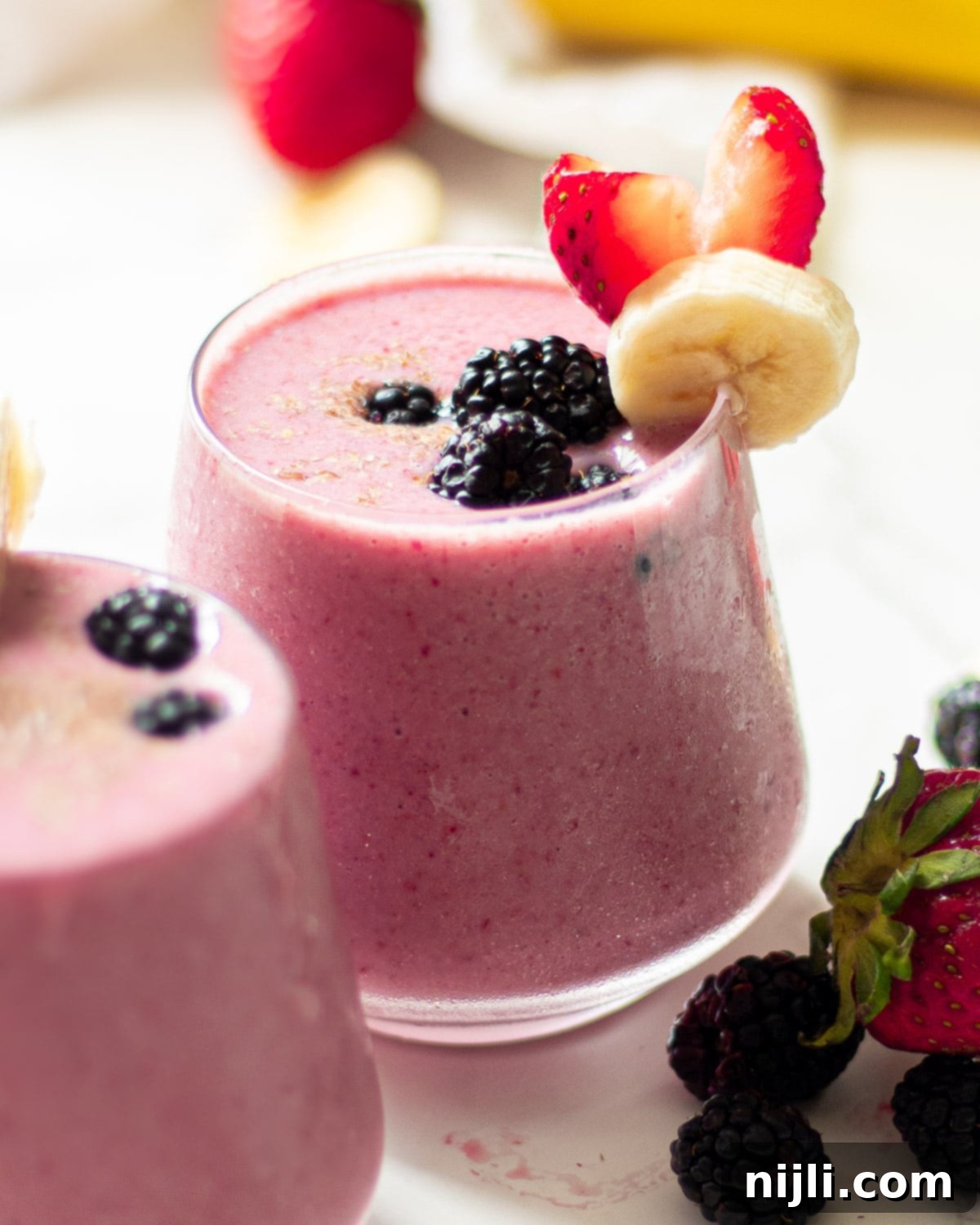 Triple Berry Banana Delight 6 blackberry strawberry banana smoothie in glasses with fruit garnish
