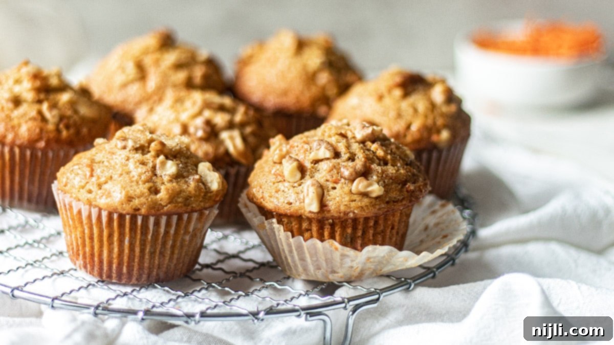 Golden Carrot Banana Muffins 3 Freshly baked banana carrot oatmeal muffins cooling on a wire rack.