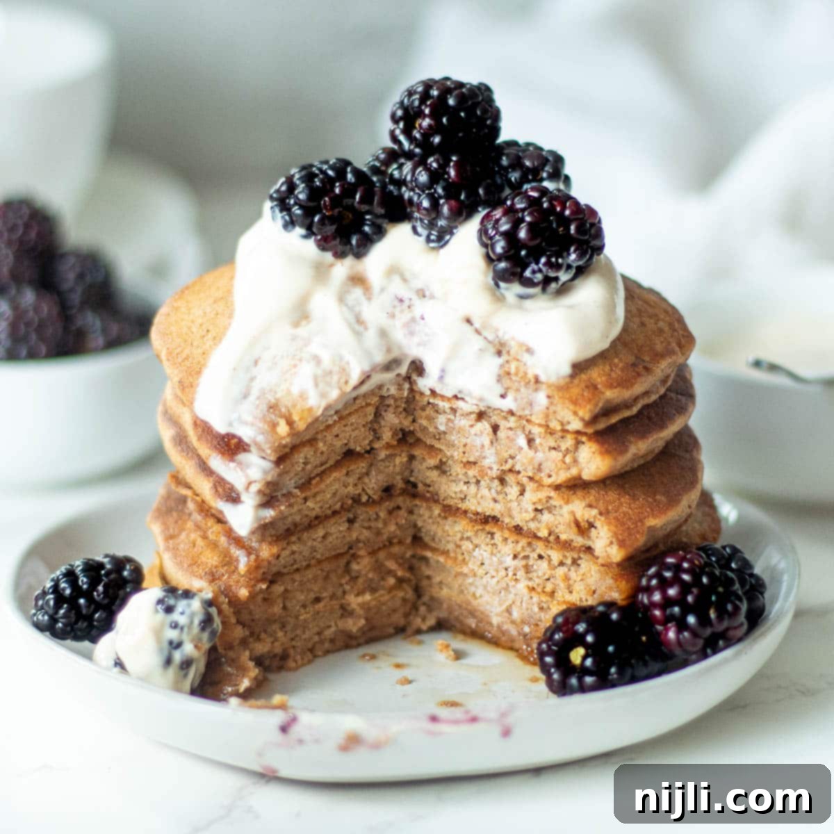Fluffy Oat Milk Bliss 2 Stacked fluffy oat milk pancakes with a slice cut out, showcasing their light and airy texture.