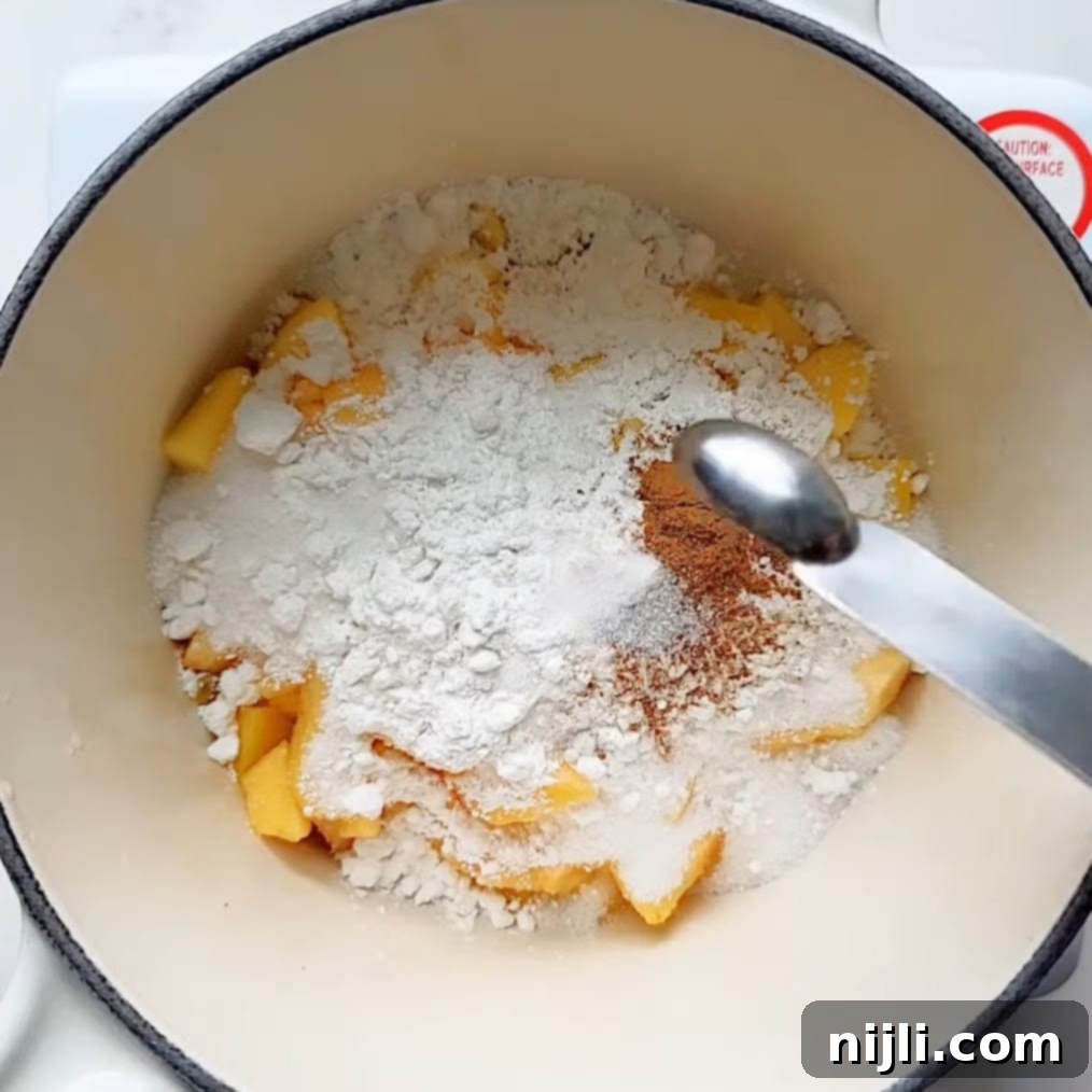Tropical Peach Mango Pie 6 mixing peaches, mangoes, and other ingredients in a saucepan for peach mango pies.