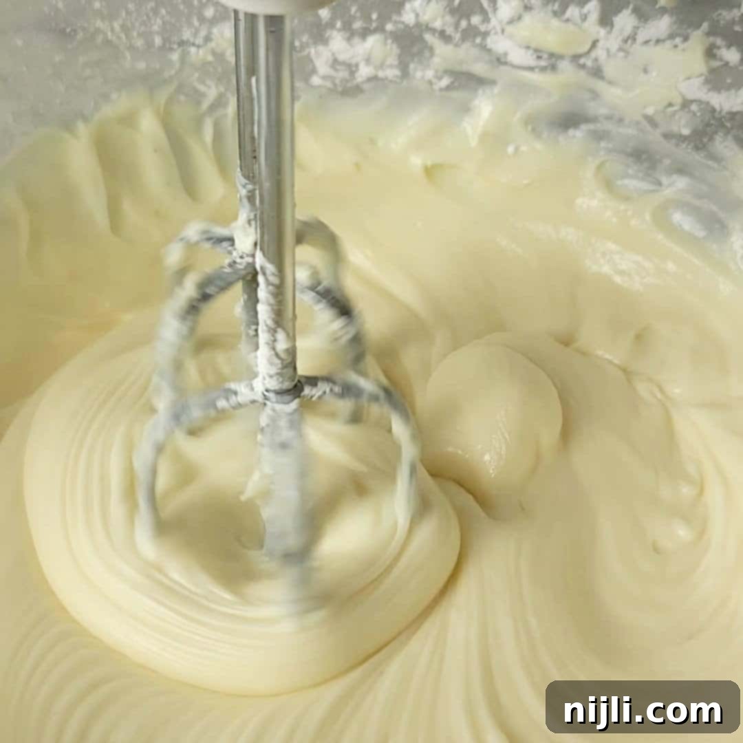 Strawberry Crunch Cheesecake 6 Mixing cream cheese, powdered sugar, vanilla, and lemon juice in a bowl with an electric mixer for a smooth cheesecake base.