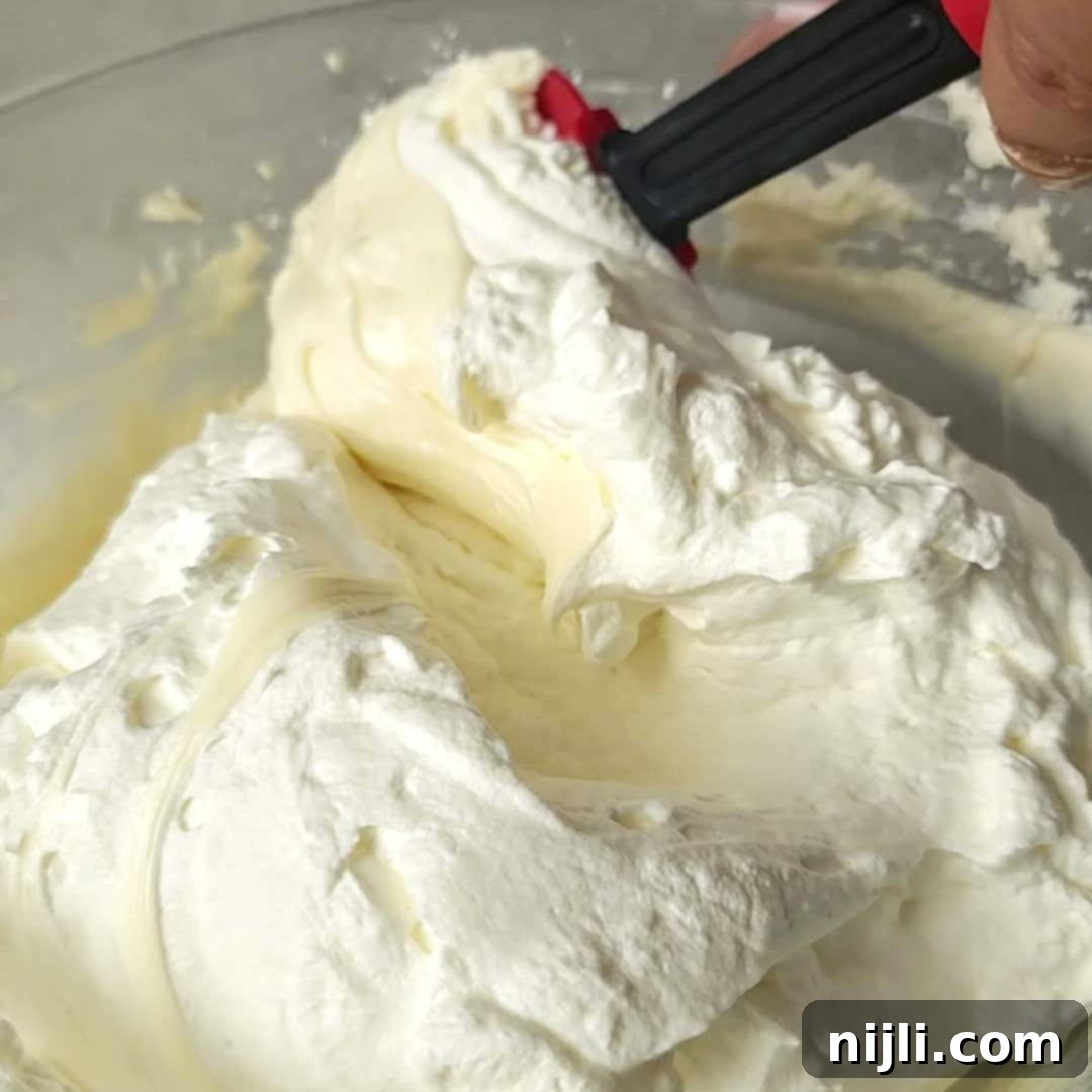Strawberry Crunch Cheesecake 8 Gently folding the whipped cream into the smooth cream cheese mixture to create a light and airy cheesecake filling.