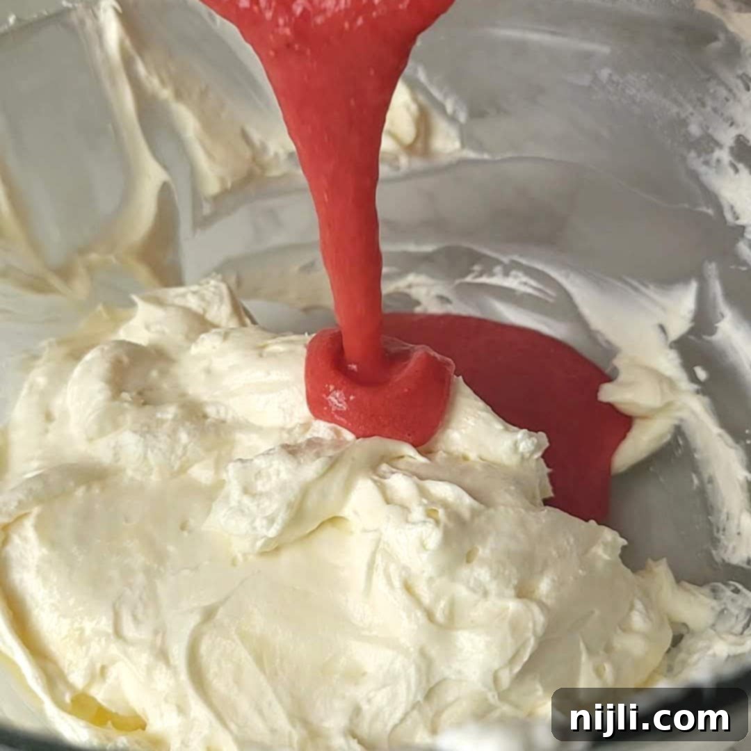 Strawberry Crunch Cheesecake 9 Adding strawberry puree to half of the cheesecake mixture to create a vibrant strawberry layer for the cheesecake.