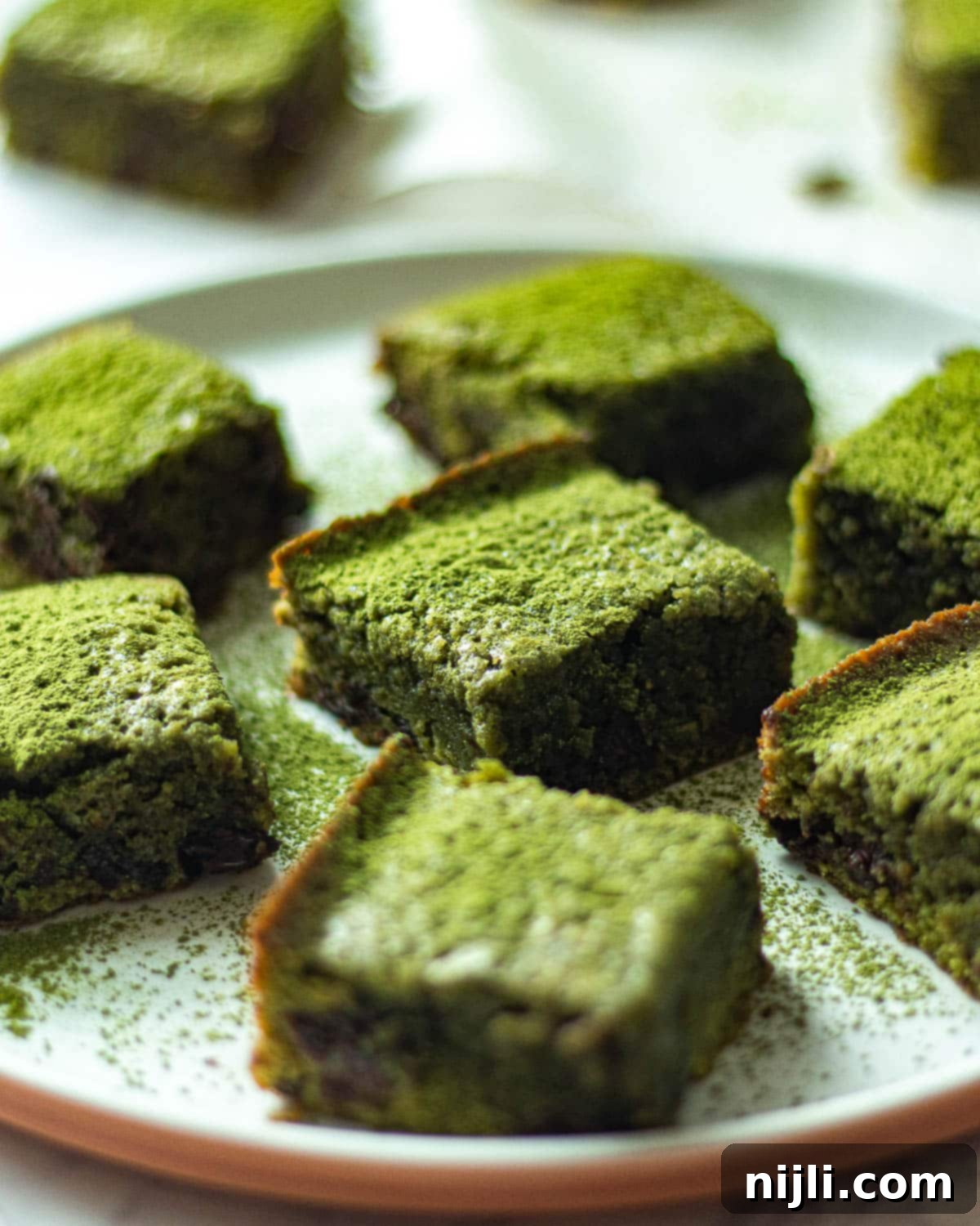 Green Tea Dream Brownies 3 Fudgy matcha brownie on a pristine white plate, showcasing its vibrant green hue and chocolate chunks