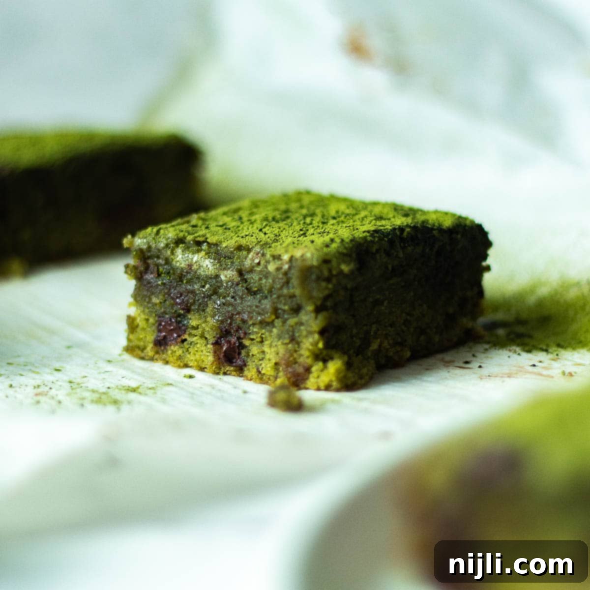 Green Tea Dream Brownies 4 Single matcha brownie resting on parchment paper, highlighting its dense, fudgy texture