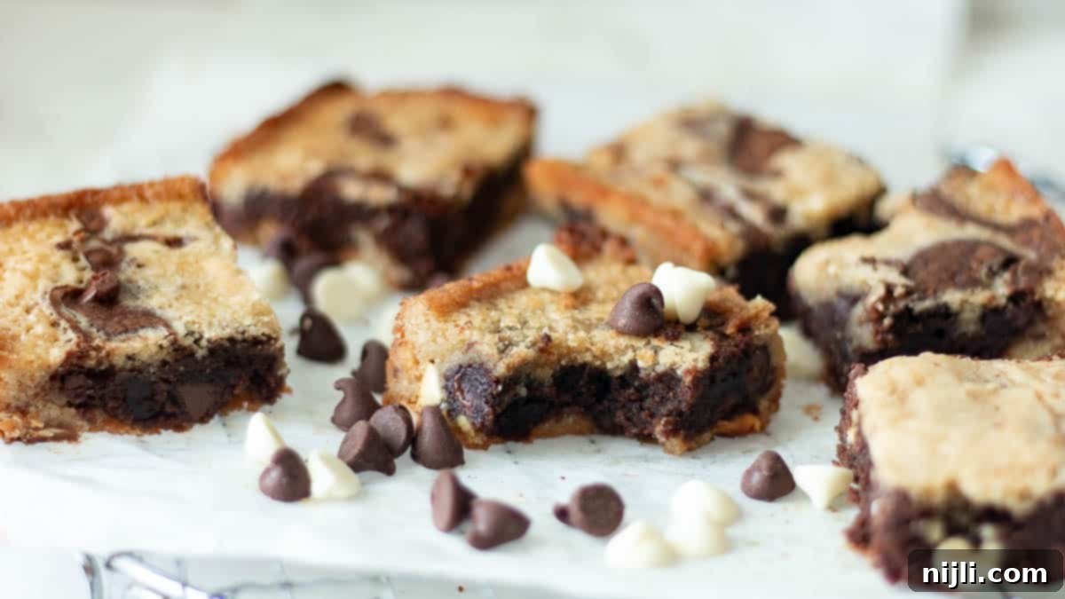 Baked blondie brownie recipe on parchment paper with chocolate chips scattered around, ready for cooling.