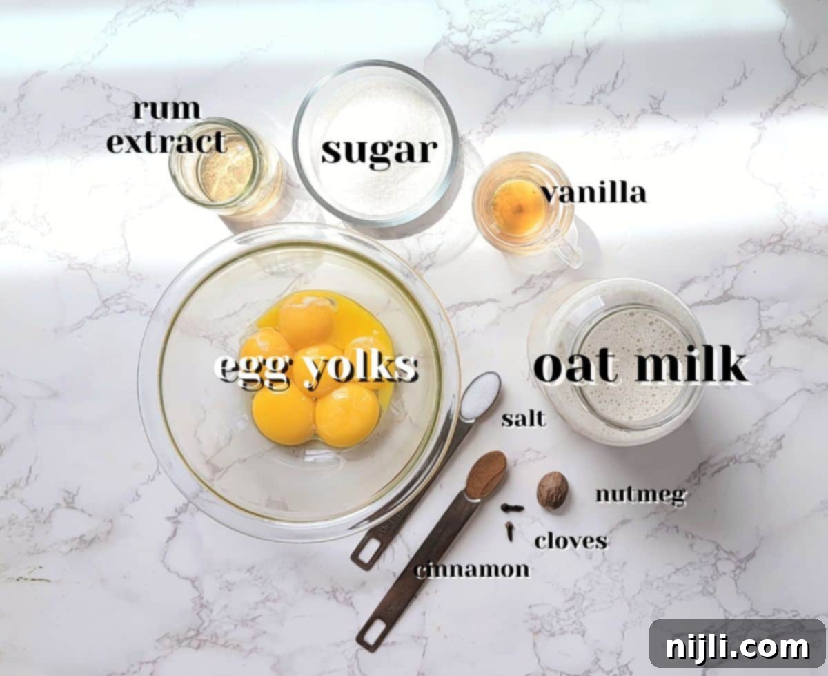 Spiced Oat Milk Cheer 4 A collection of ingredients for oat milk eggnog, including oat milk, spices, and eggs, arranged on a rustic surface.