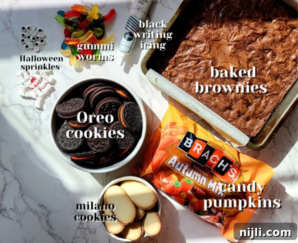 Tombstone Brownies 4 A selection of ingredients for graveyard brownies, including brownies, Oreo cookies, Milano cookies, icing pen, gummy worms, and various Halloween candies.