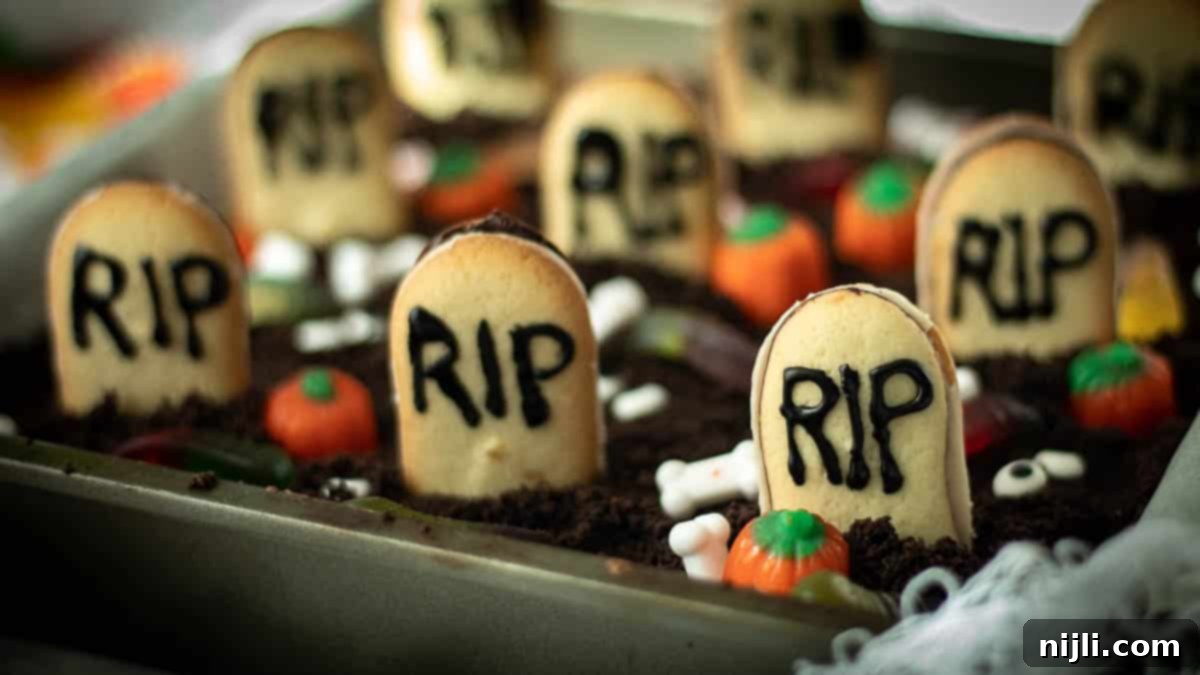 Tombstone Brownies 10 A festive tray of Halloween desserts, including graveyard brownies and pumpkin-themed treats, perfect for a gathering.