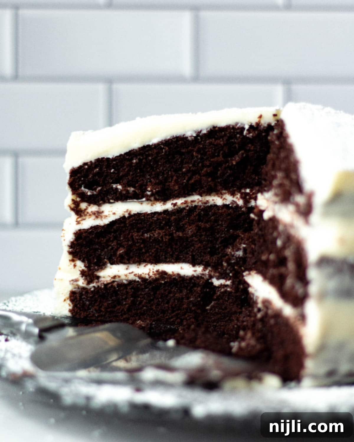 Decadent Chocolate Cake with Velvety Cream Cheese Frosting 14 triple layer chocolate cake with cream cheese frosting cut on a tray