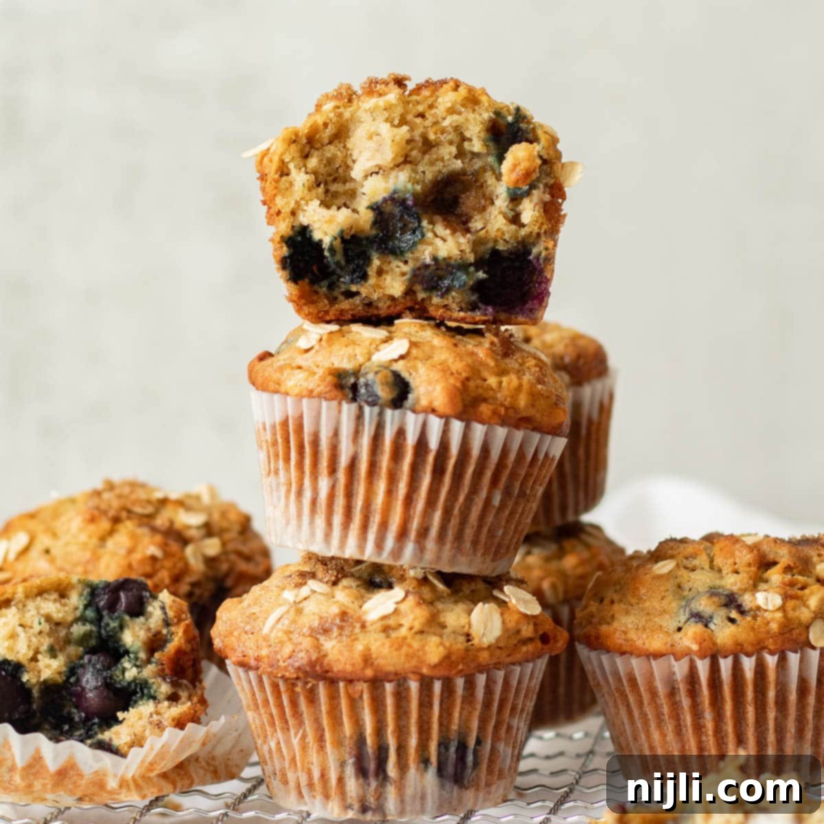 stacked healthy banana blueberry oatmeal muffins on a cooling rack